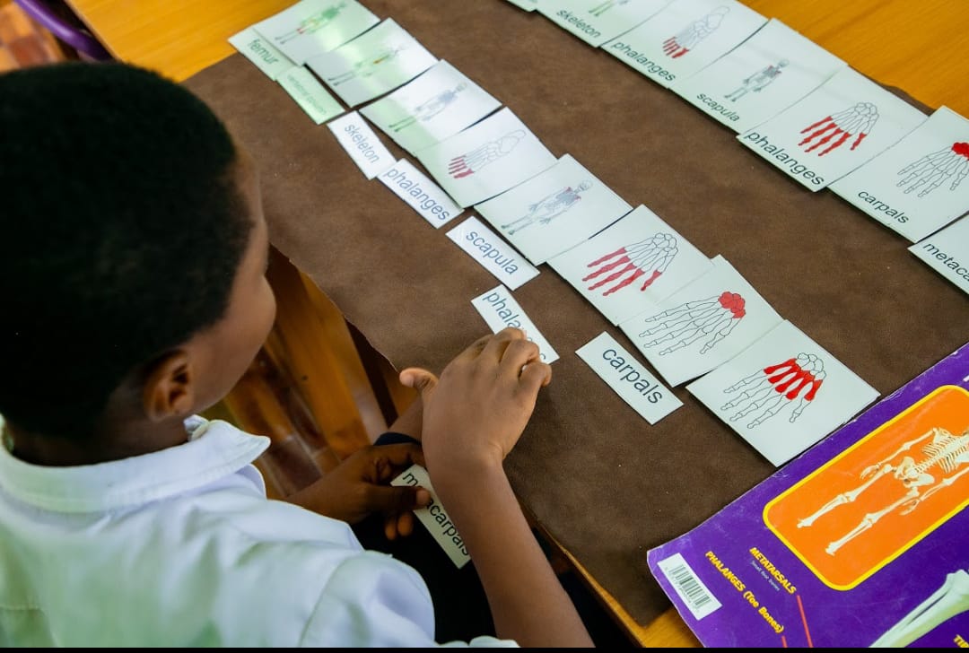 Teacher assisting a pupil with handwriting practice at Ambassadors Bilingual School