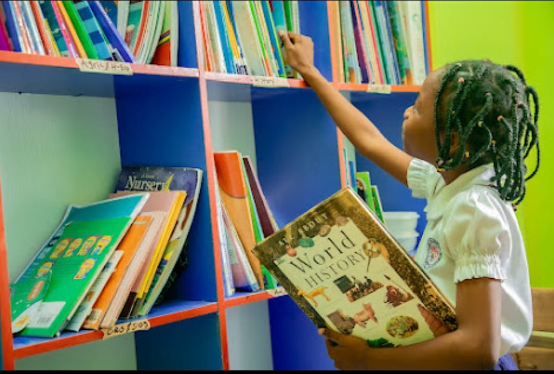Pupil choosing a book in the well-equipped school library at Ambassadors Bilingual School