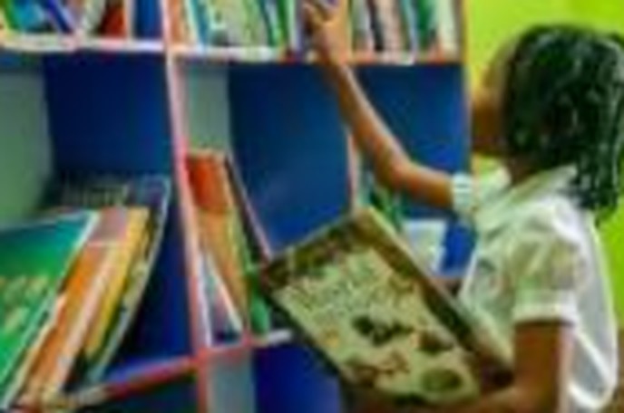 Pupil choosing a book in the well-equipped school library at Ambassadors Bilingual School